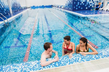 Genç yetişkinler eğleniyor kapalı yüzme havuzunda konuşuyor