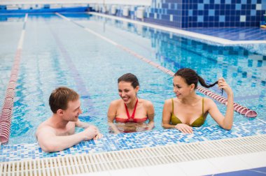 Genç yetişkinler eğleniyor kapalı yüzme havuzunda konuşuyor