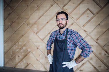 Eldiven ve gözlük ellerle kalça üzerinde giyen genç erkek marangoz