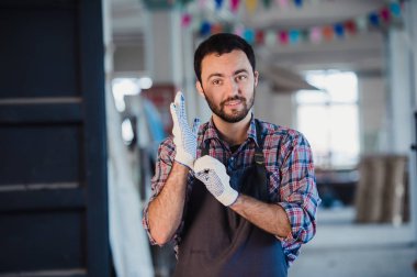 Eldiven giymiş atölyede çalışan bir marangoz portresi