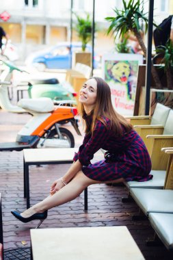 Güzel gülümseme Menekşe damalı elbise ve bir kafe yakınındaki vintage eski scooter yaz gününde giyen genç çekici kız