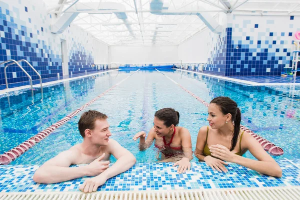 Adultos jóvenes divirtiéndose hablando en la piscina al aire libre — Foto de Stock