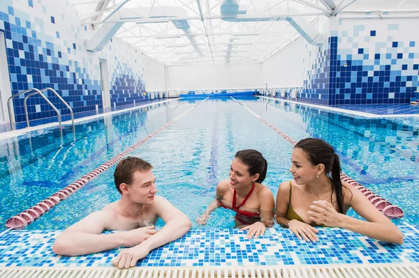 Giovani adulti che si divertono a parlare in piscina al coperto — Foto Stock