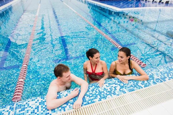 Genç yetişkinler eğleniyor kapalı yüzme havuzunda konuşuyor