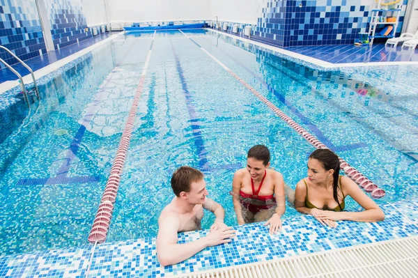 Giovani adulti che si divertono a parlare in piscina al coperto — Foto Stock