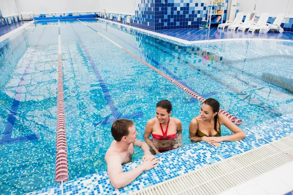 Giovani adulti che si divertono a parlare in piscina al coperto — Foto Stock