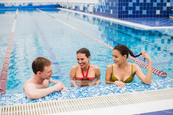 Genç yetişkinler eğleniyor kapalı yüzme havuzunda konuşuyor