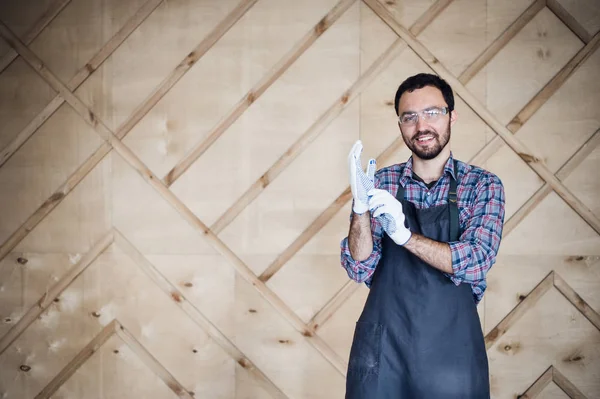 Eldiven giymiş atölyede çalışan bir marangoz portresi