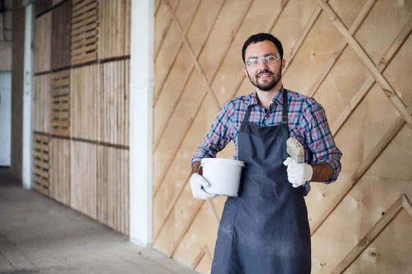 Eldiven ve gözlük ellerle kalça üzerinde giyen genç erkek marangoz