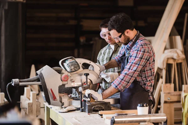 Dos carpinteros cortando tablón de madera con una sierra circular —  Fotos de Stock