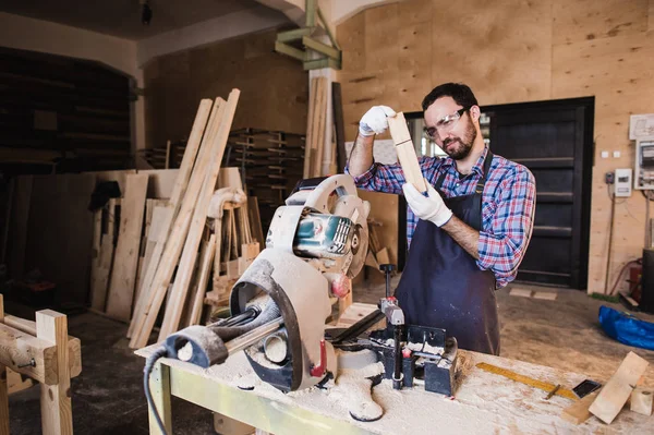 Carpintero trabajando en una sierra eléctrica cortando algunas tablas, lleva gafas de seguridad — Foto de Stock