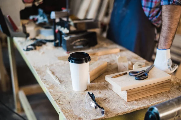 Moderno lugar de trabajo de carpintería con tableta, café, tijeras y piezas de madera en la mesa, en el taller —  Fotos de Stock
