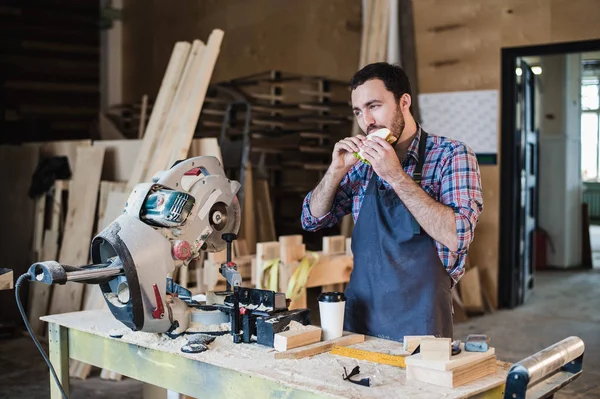 Alegre carpintero almorzando comiendo sándwich en un taller — Foto de Stock