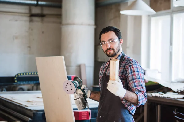 Carpintero con amoladora eléctrica en su taller — Foto de Stock