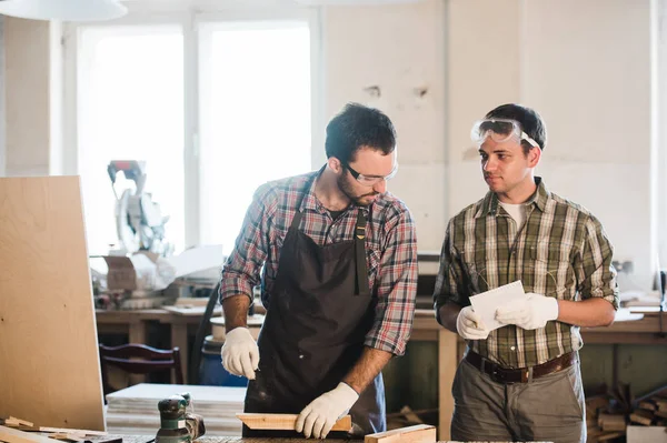 Deux hommes polissent les planches. charpentier avec une ponceuse — Photo