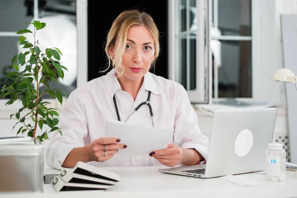 Médico femenino adulto medio leyendo documentos en el escritorio del consultorio — Foto de Stock