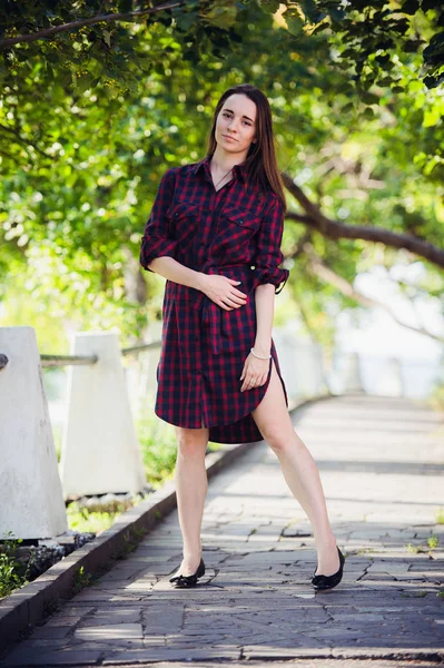 Vackra, vackra kvinnan i casual rutig klänning promenader på park utomhus. Street mode stil. — Stockfoto