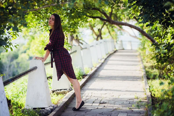 Attraktiv ung kvinde viser hendes ben, mens hun går i parken - Stock-foto