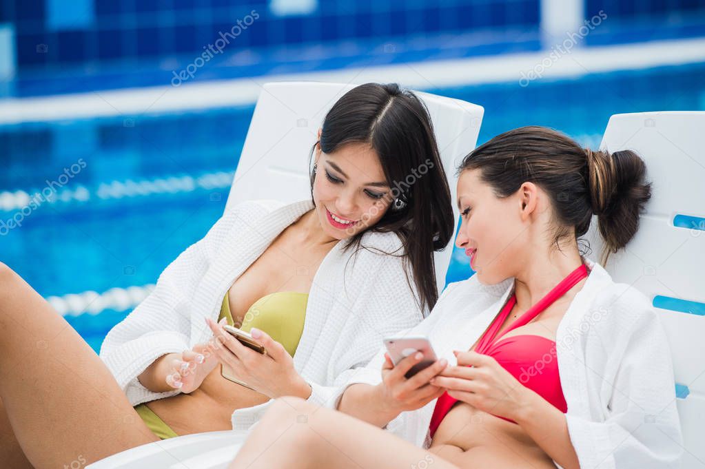 Young girls friends messaging with friend on her smartphone. Relaxation spa and technology social networks concept.