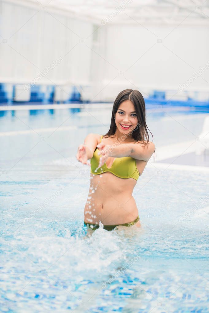 Pretty young woman going out of the swimming pool