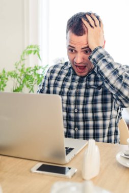 Kafede dizüstü bilgisayarda görünen endişe shoked adam