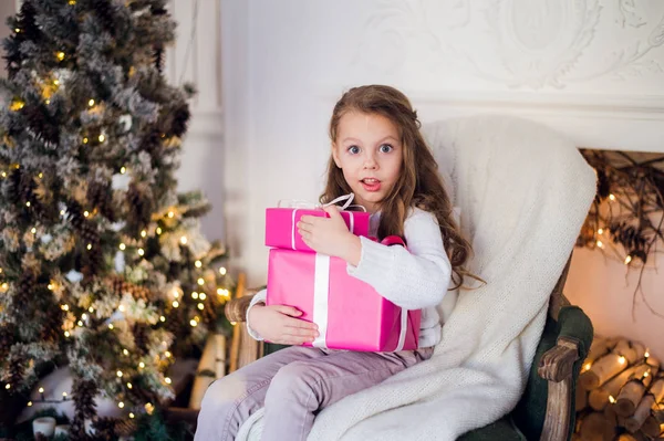 Image de belle fille avec des boîtes-cadeaux assis sur un fauteuil à la maison. Décoré arbre de Noël fond — Photo