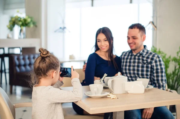 Aile, ebeveynlik, teknoloji insanlar kavramı - mutlu anne, baba ve küçük kız akşam yemeği, çocuk alarak fotoğraf yanında smartphone restoranda yakın