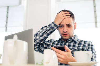 Kafede dizüstü bilgisayarda görünen endişe shoked adam