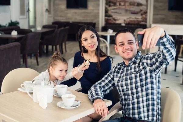 Family, parenthood, technology people concept - happy mother, father and little girl having dinner taking selfie by smartphone at restaurant — Stock Photo, Image