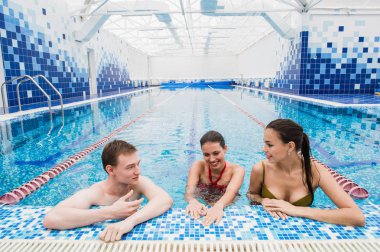 Genç yetişkinler eğleniyor kapalı yüzme havuzunda konuşuyor