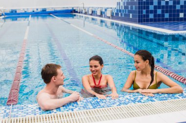 Genç yetişkinler eğleniyor kapalı yüzme havuzunda konuşuyor