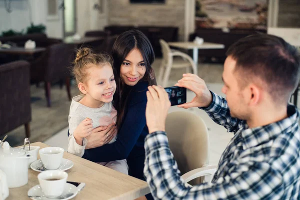 Família, paternidade, tecnologia, conceito de pessoas - pai feliz tirando fotos de sua filhinha e esposa por smartphone jantando no restaurante — Fotografia de Stock