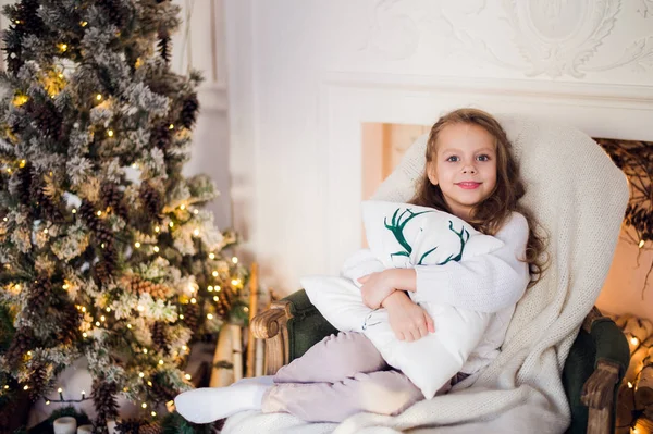Portret van een schattig klein meisje kussen thuis tegen kerstboom omarmen — Stockfoto