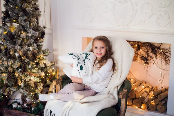 リトル プリンセスは自宅のクリスマス ツリーが鹿枕を肘掛け椅子に座る — ストック写真