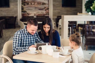 Aile, ebeveynlik, teknoloji insanlar kavramı - mutlu anne, baba ve küçük kız ile tablet pc bilgisayar restoranda akşam yemeği