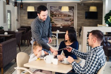 Restoran ve tatil kavramı - kafe mutlu aile için menü veren garson