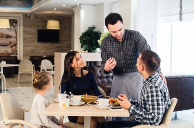 Emir alan aile birlikte akşam yemeği masada samimi gülümseyen garson
