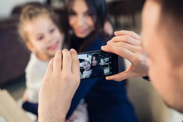 Rodzina, rodzicielstwo, technologii, koncepcja ludzie - szczęśliwy ojciec biorąc zdjęcie jego mała córka i żona przez smartfona, obiad w restauracji — Zdjęcie stockowe