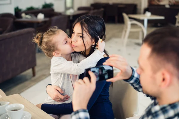 Familia, paternidad, tecnología, concepto de personas - padre feliz tomando fotos de su pequeña hija y esposa por teléfono inteligente cenando en el restaurante — Foto de Stock