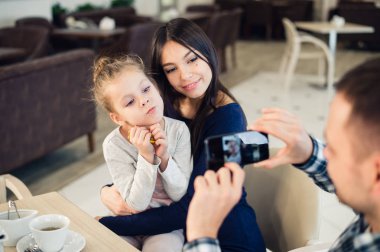 Aile, ebeveynlik, teknoloji, insan kavramı - mutlu baba alarak fotoğrafı onun küçük kızı ve karısı yanında smartphone restoranda akşam yemeği