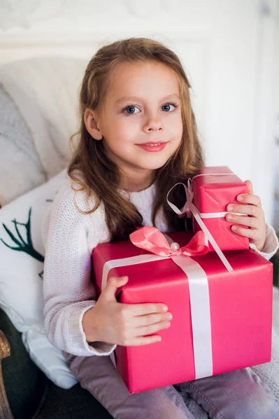 Mutlu kız Noel hediyeleri Noel arifesinde dekore edilmiş şömineli rahat ışık oturma odasında açmalarına
