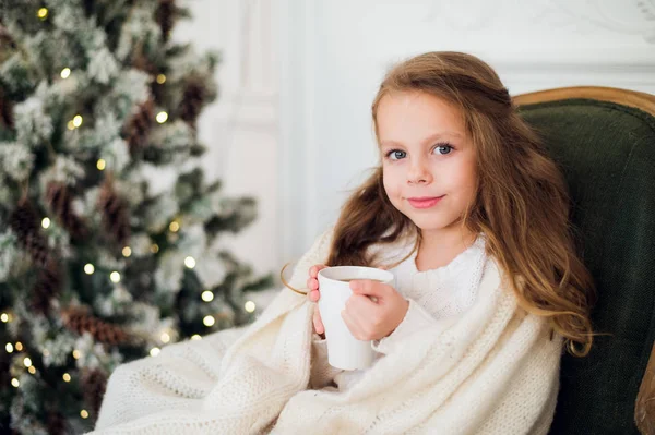 Meisje consumptiemelk in de buurt van de kerstboom in ochtend thuis — Stockfoto