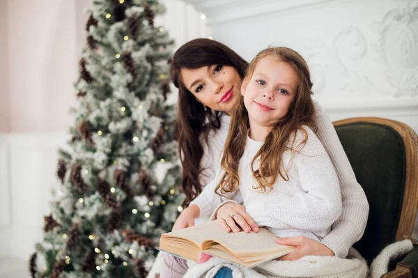 Meisje en haar moeder lezen boek bij Kerstmis — Stockfoto