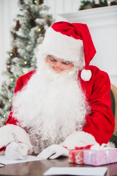 Santa Claus aan tafel zitten en schrijven op papier — Stockfoto