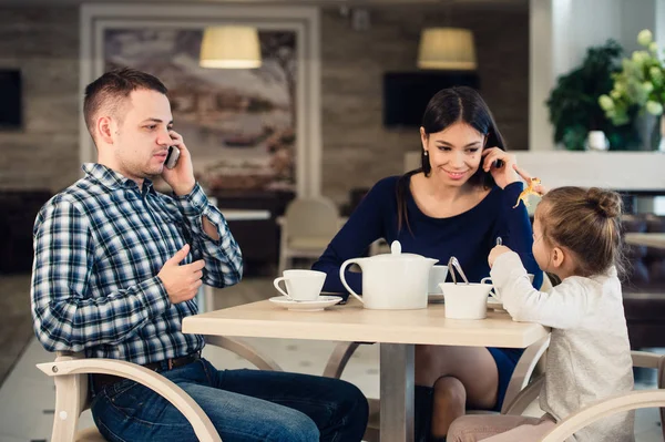 Caucásico madre y pequeño niño niña en restaurante mientras su ocupado padre hablando de teléfono celular . — Foto de Stock