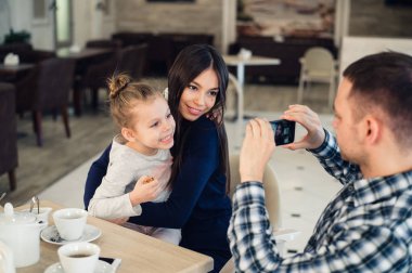 Aile, ebeveynlik, teknoloji, insan kavramı - mutlu baba alarak fotoğrafı onun küçük kızı ve karısı yanında smartphone restoranda akşam yemeği