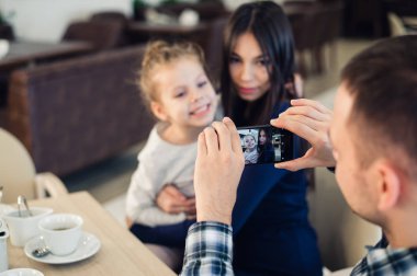 Aile, ebeveynlik, teknoloji, insan kavramı - mutlu baba alarak fotoğrafı onun küçük kızı ve karısı yanında smartphone restoranda akşam yemeği