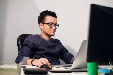 Yoğun çalışma. Onun iş yerinde otururken gözlük laptop dalgın genç yakışıklı adam