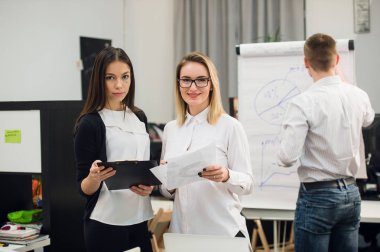 Konuşmayı adam meslektaşım iş stratejisi üzerinde flip grafik çizim sırasında iki güzel Ofis çalışanları.