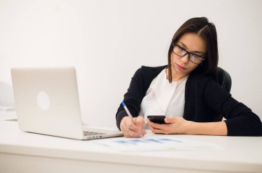 Bilgisayarlı bir iş kadını portresi ofisindeki bir belgeye yazıyor.